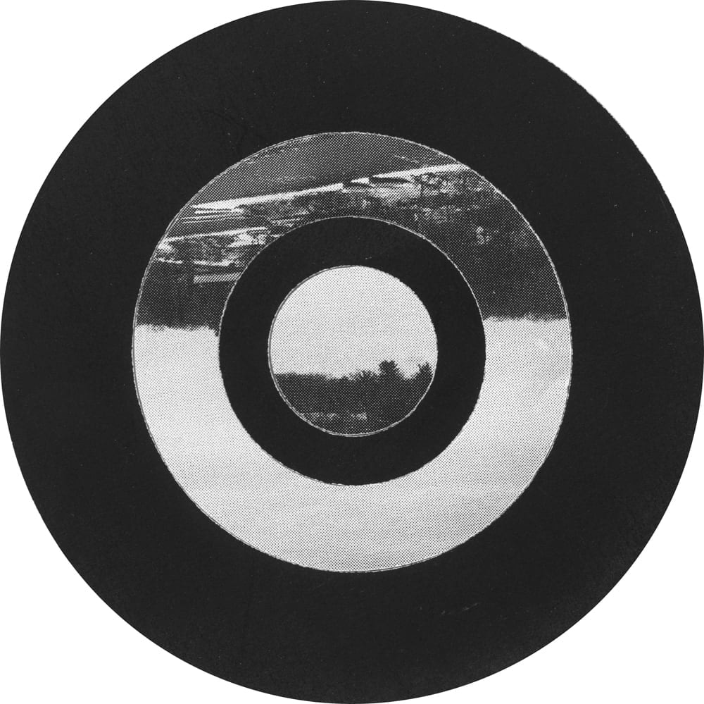 Black circular field with concentric photographic rings of pale sky and a dark landscape horizon.