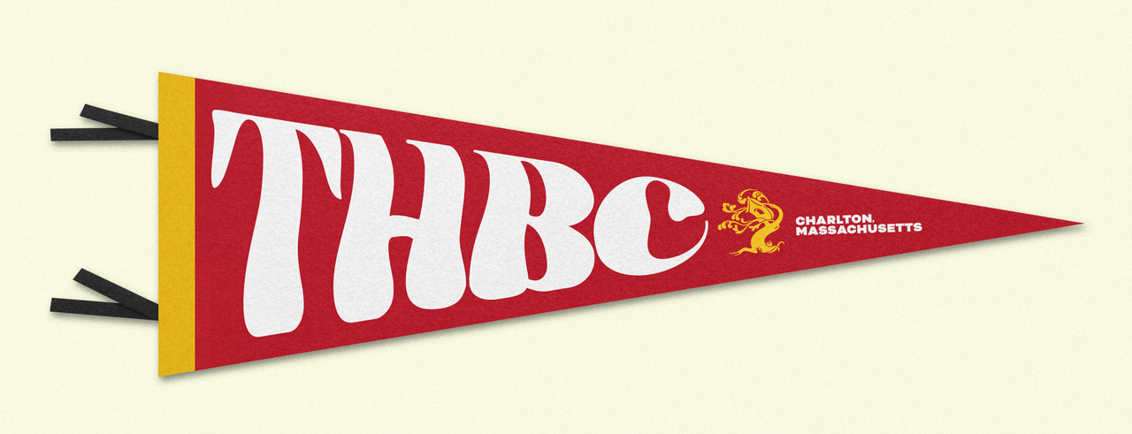 Burgundy triangular THBC pennant with large cream letters and black streamers, on pale cream.