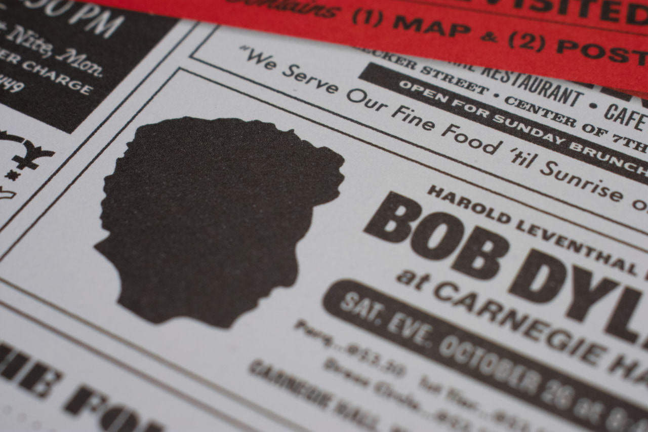 Close-up of a printed Bob Dylan flyer with a head silhouette and bold black typography.
