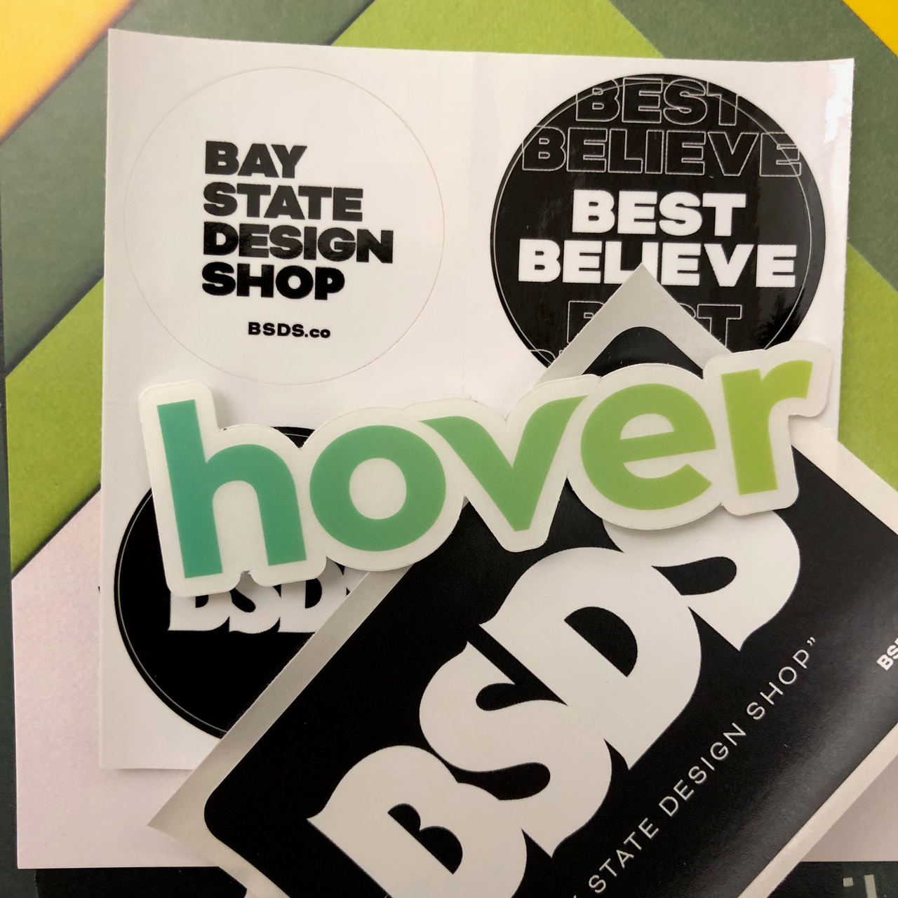 Collection of black-and-white BSDS and Best Believe stickers with a large green Hover sticker.