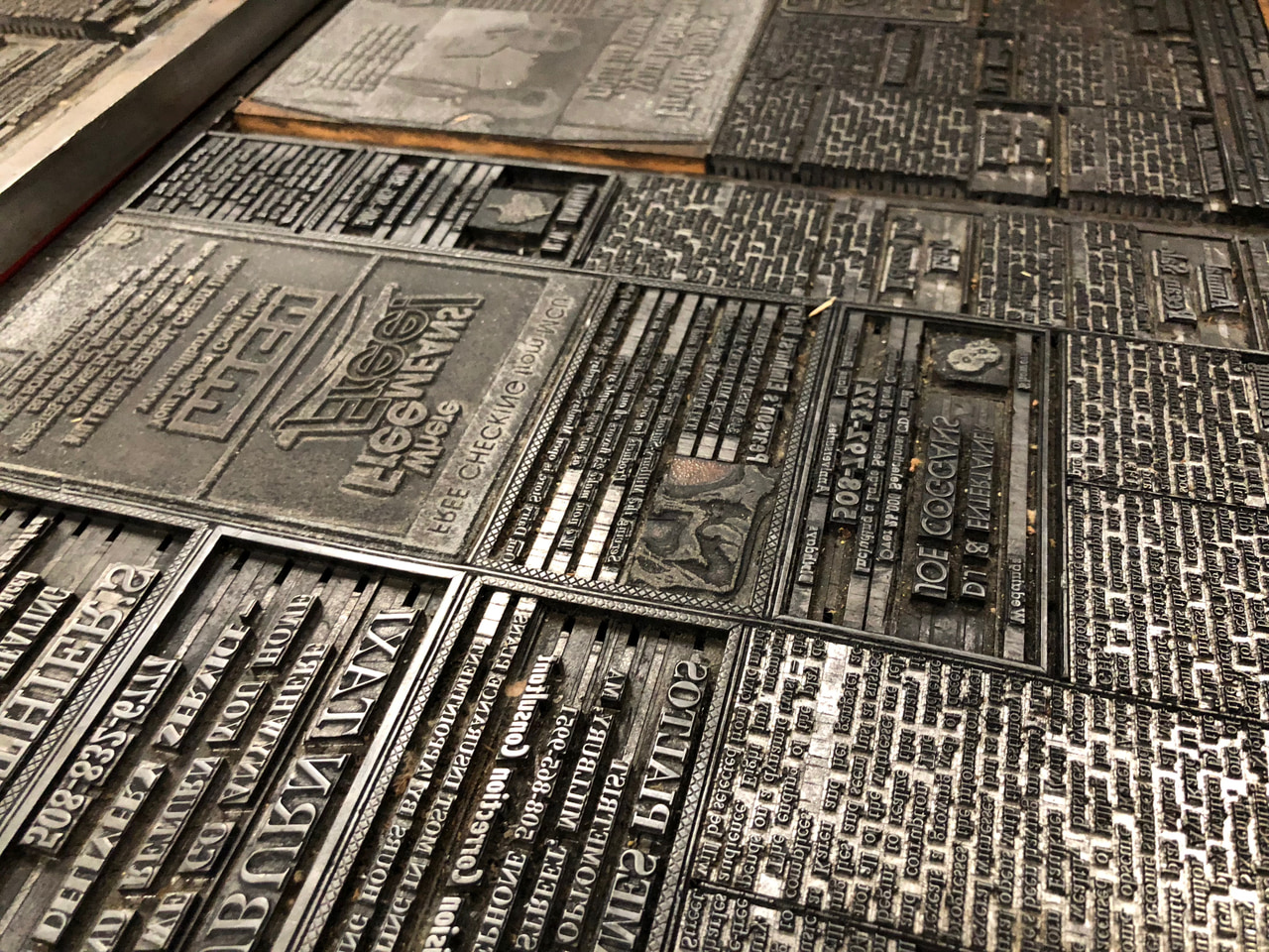 Open drawers densely filled with metal printing type and small engraved blocks.