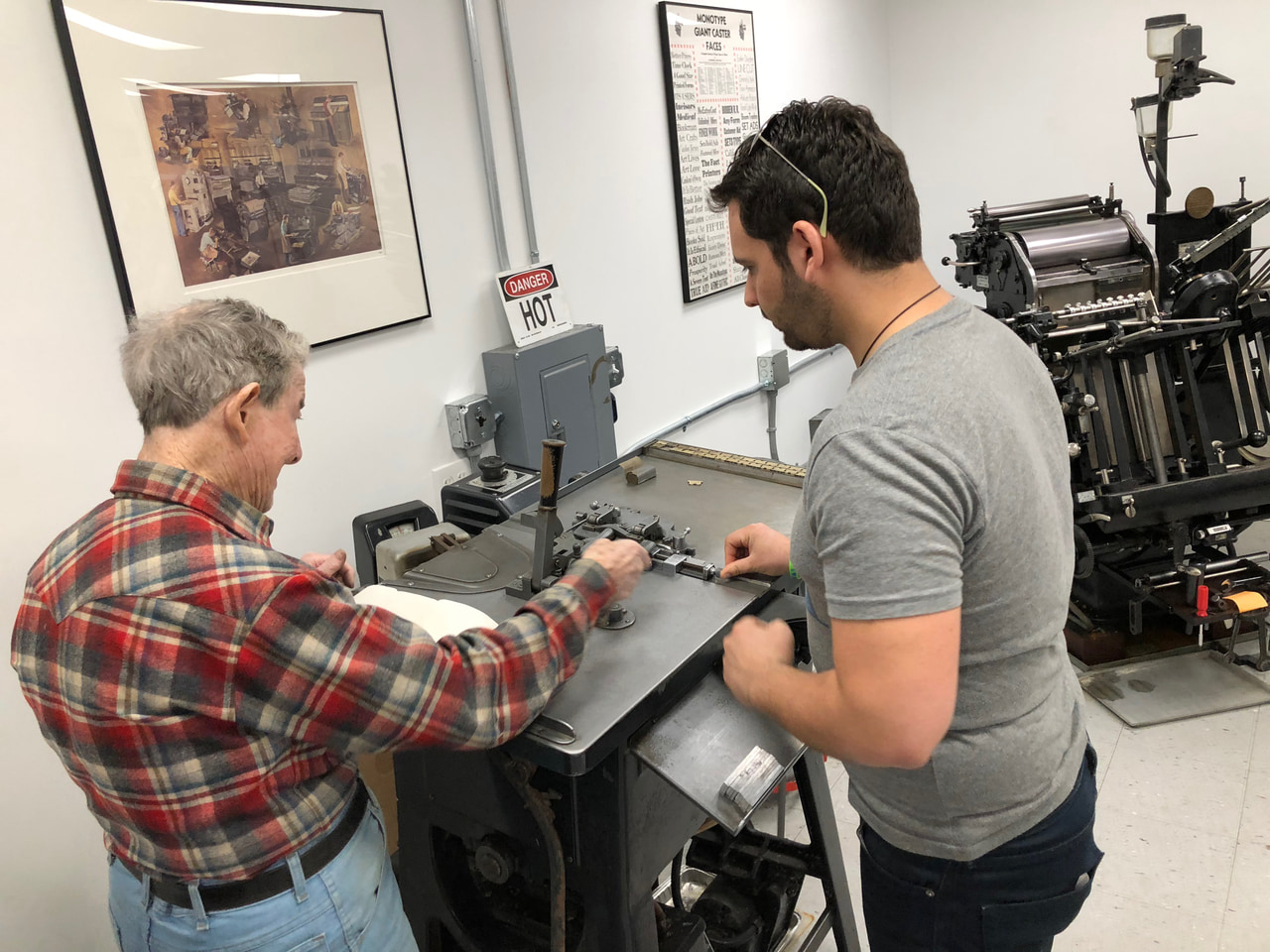 Two people working together at a printing press in a museum workshop.