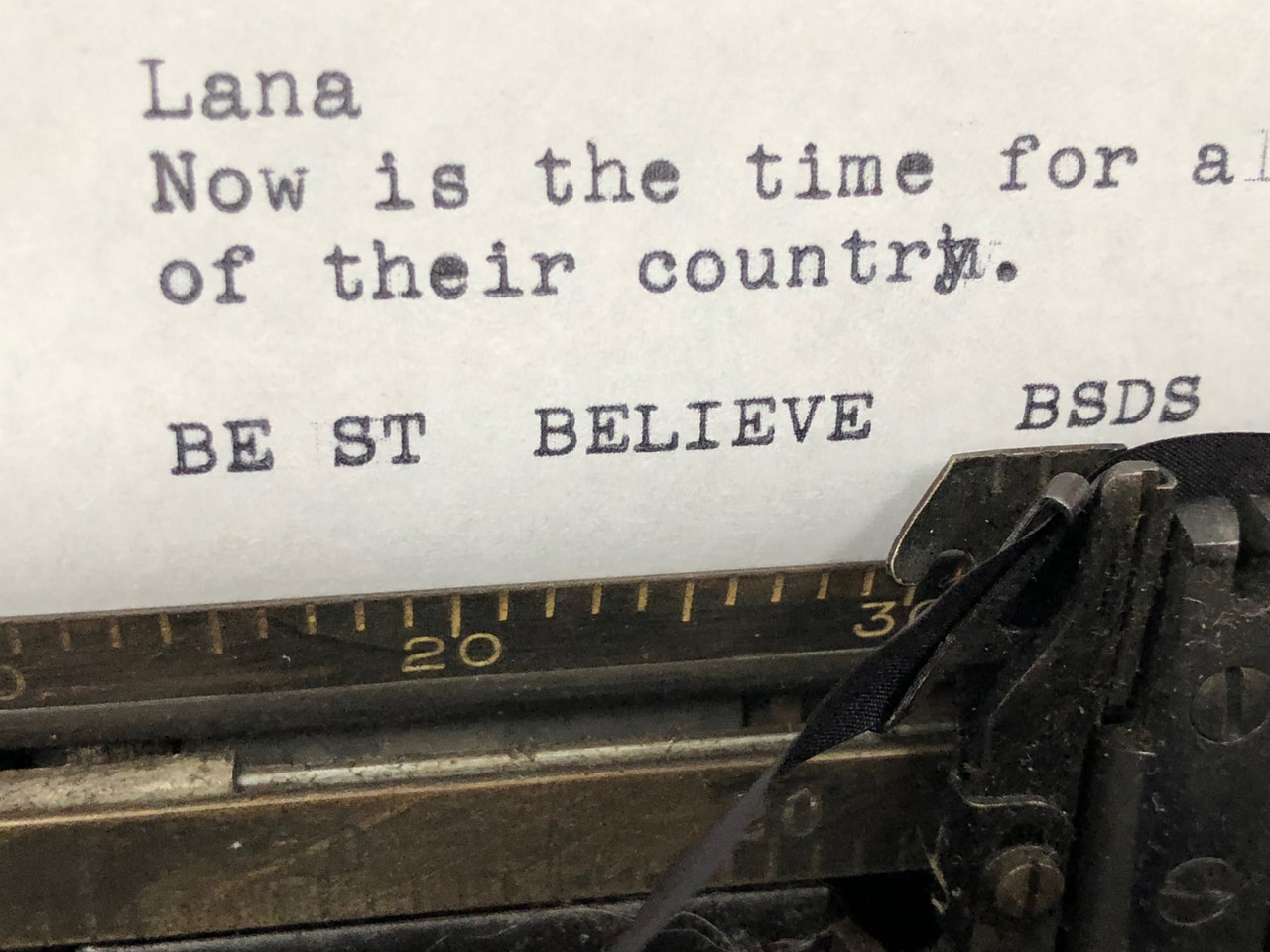 Close-up of a typewriter printing the words Be St Believe BSDS below other sample text.