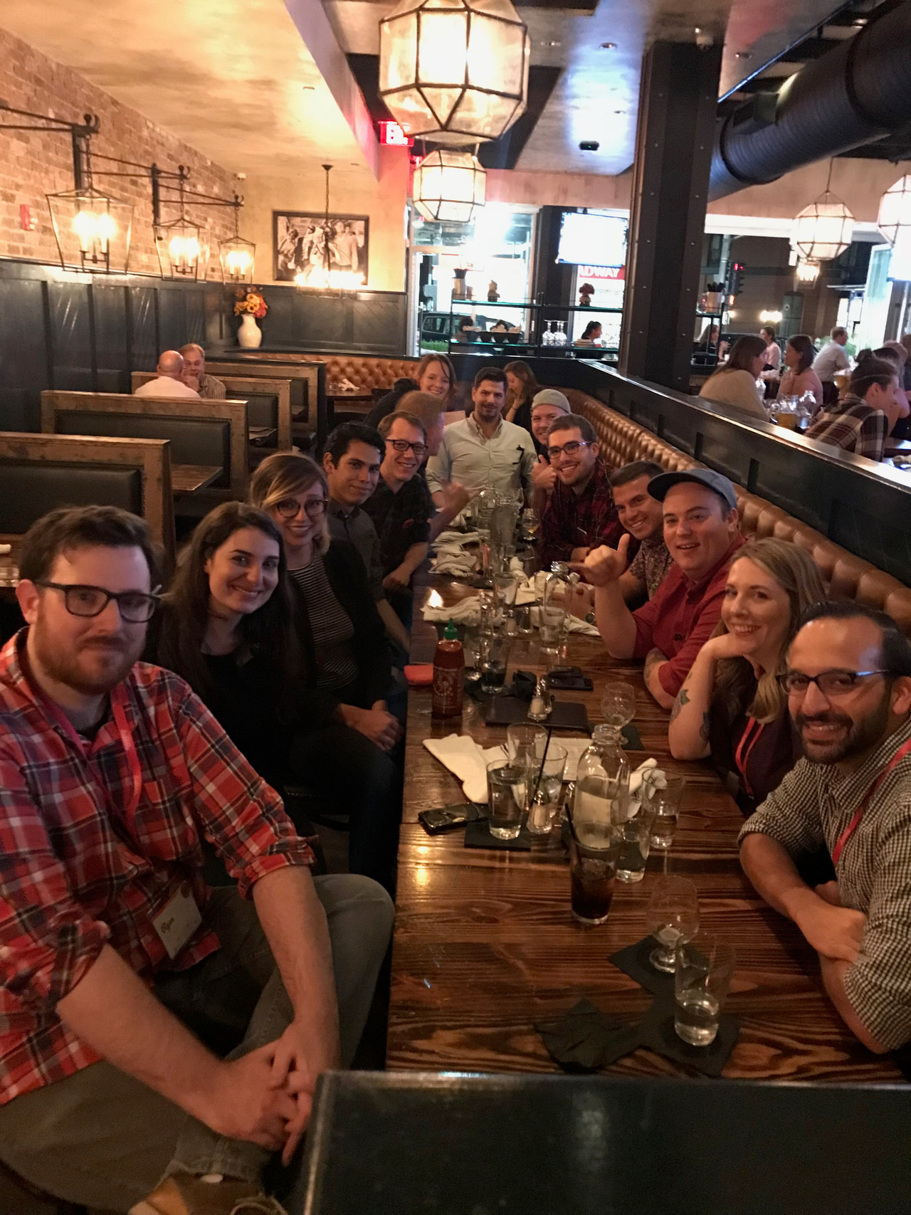 Long table of people gathering for a meal and drinks inside a restaurant.