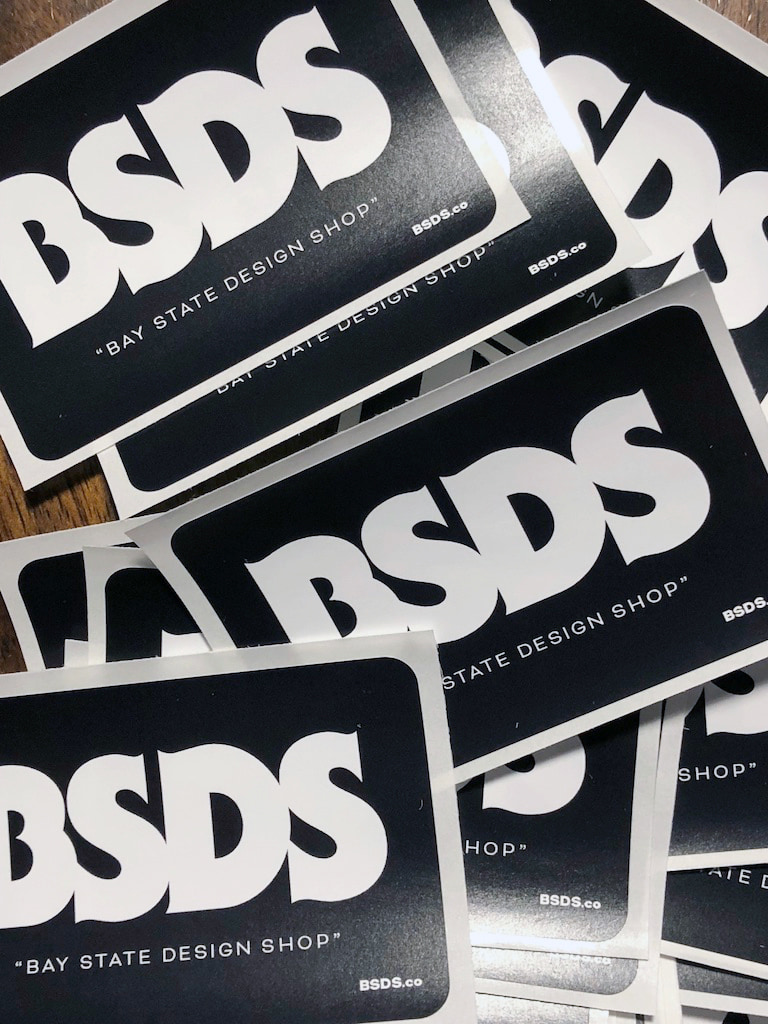 Overlapping black stickers with large white BSDS lettering.
