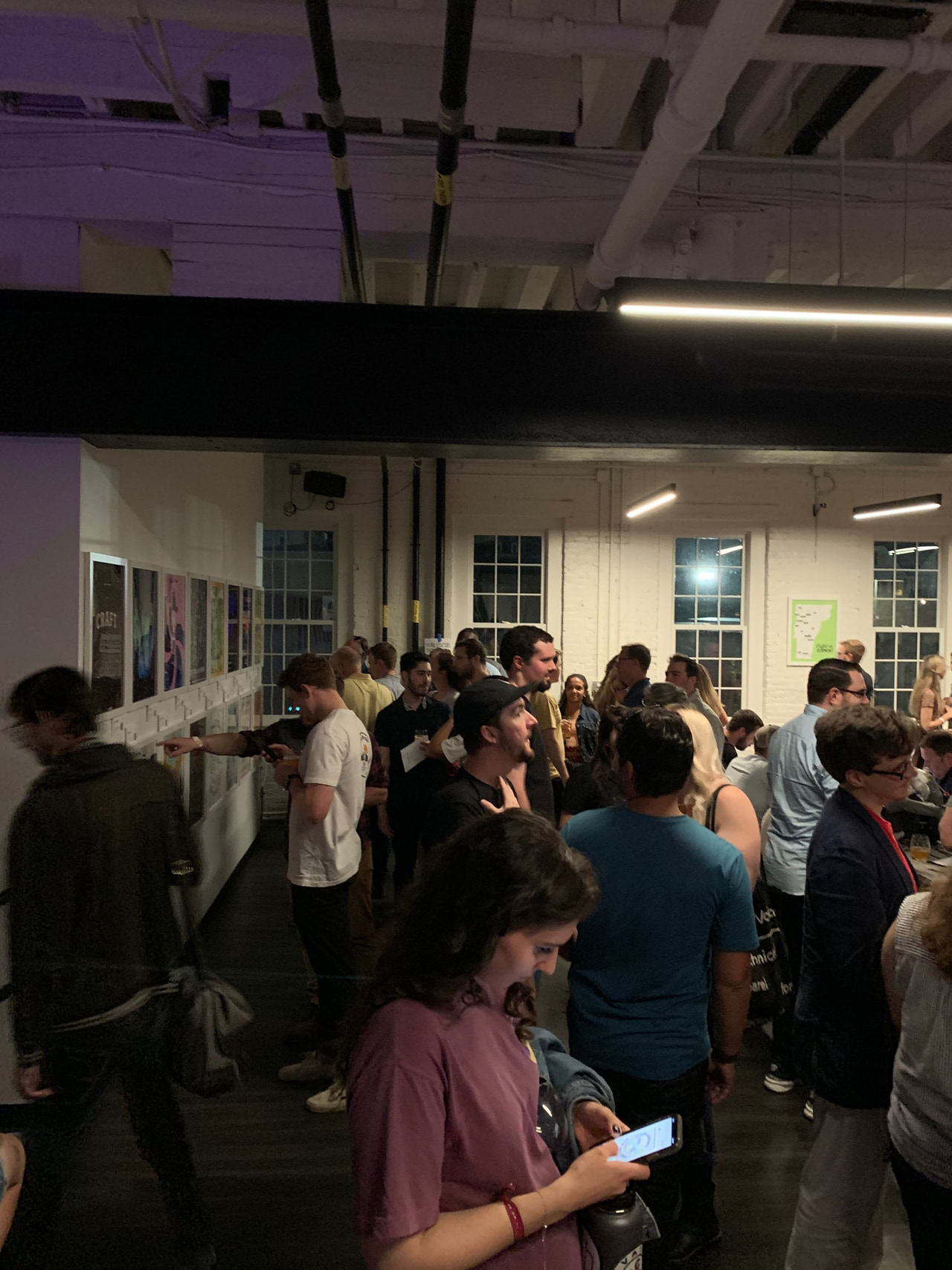 People gathered beneath exposed ceiling beams at an indoor design event.