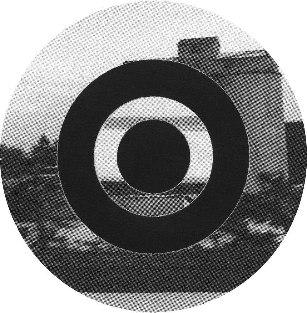 Black circular ring over a black-and-white photograph of a building and a dark tree line.