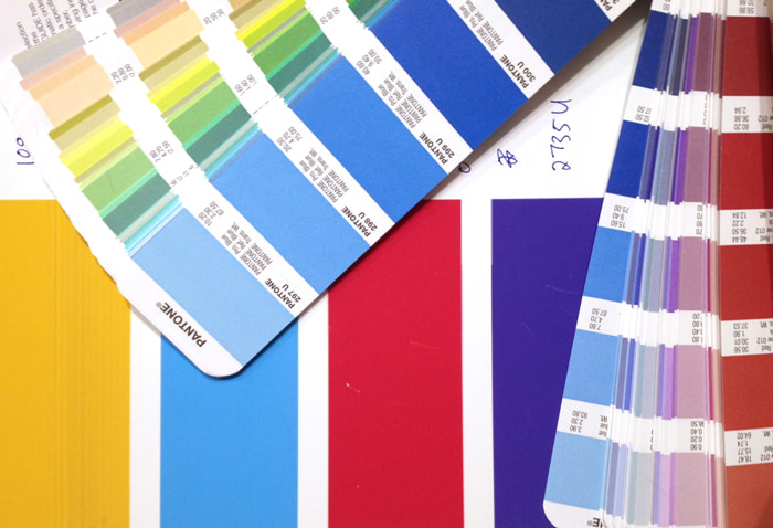Color-swatch cards arranged over broad cyan, magenta, yellow, and blue bars.