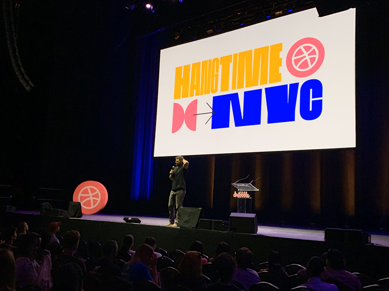 A speaker onstage beneath a bright Hang Time NYC graphic.