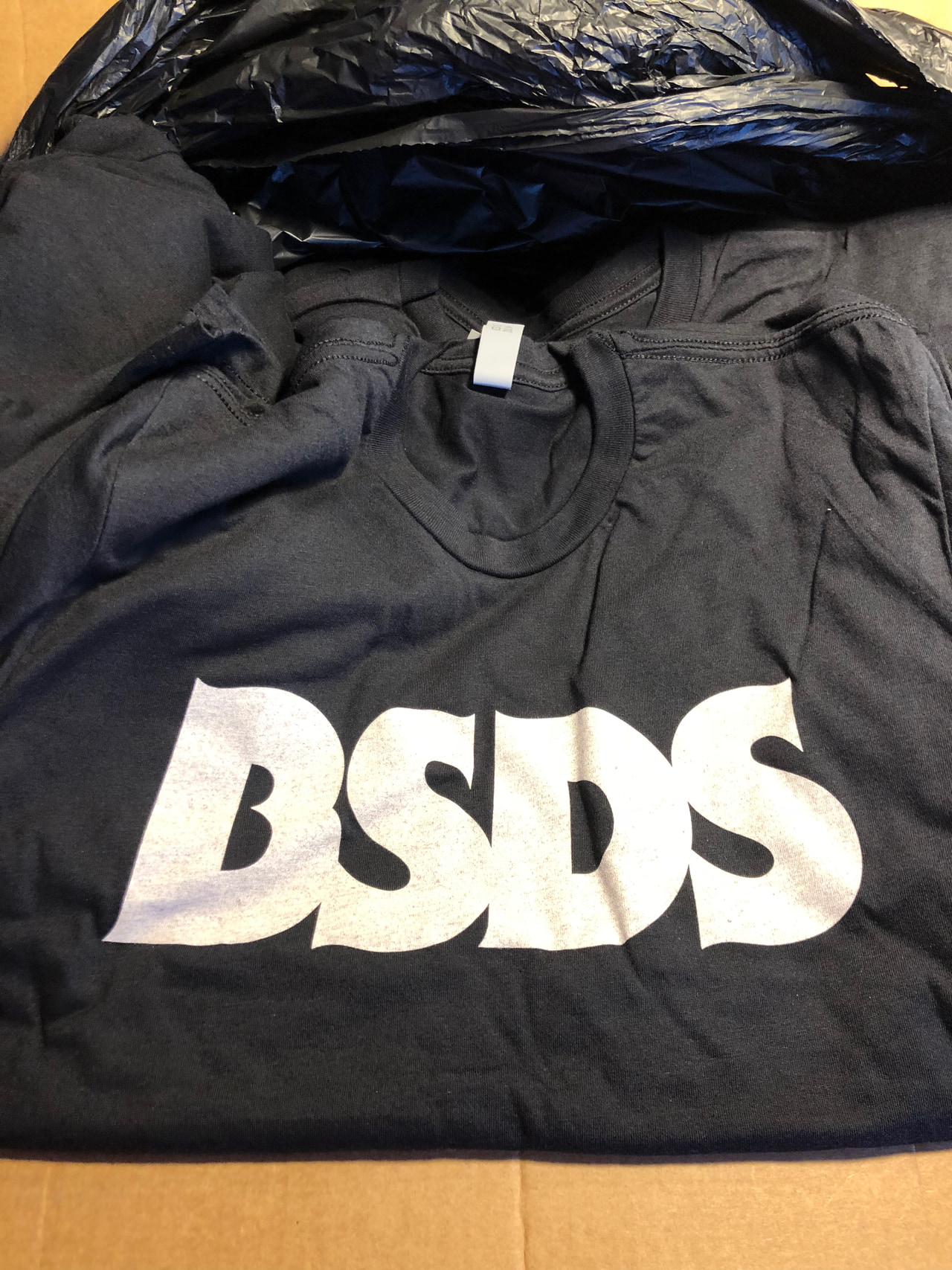 Black T-shirt laid flat with a large white BSDS wordmark.
