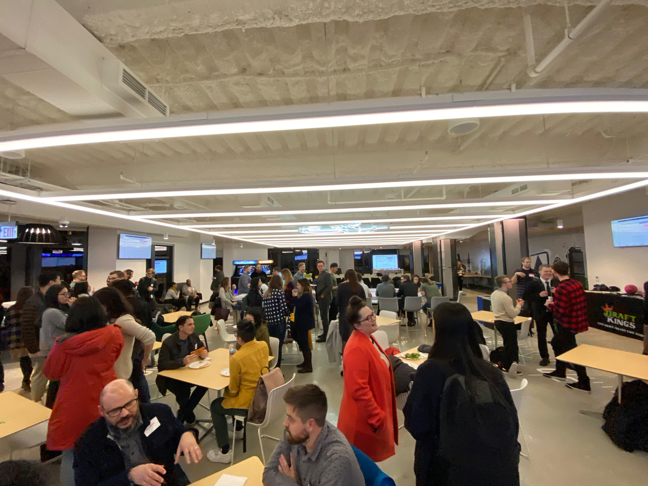 An indoor crowd beneath exposed ceiling beams.
