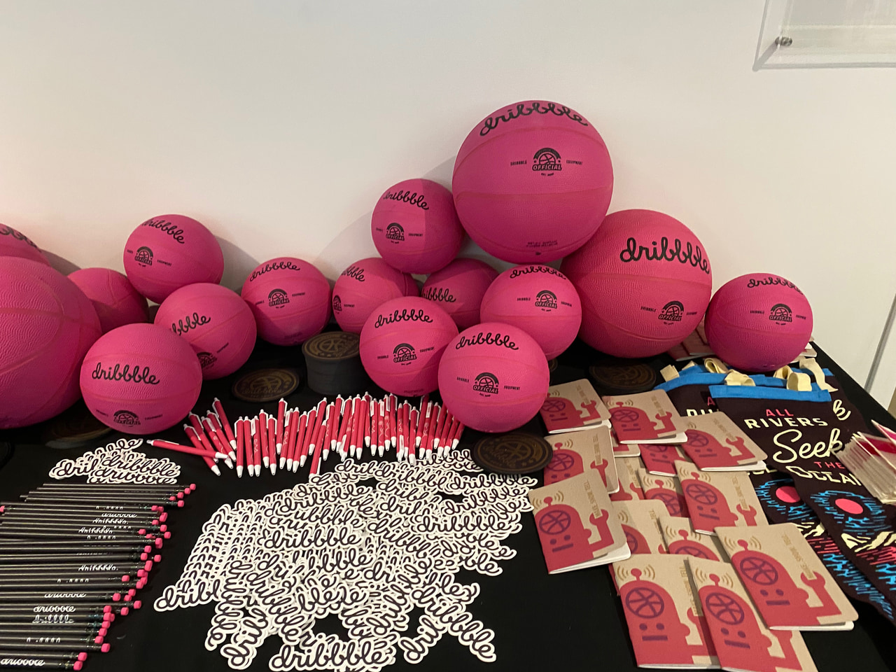 Pink branded basketballs piled behind a table of stickers and printed merchandise.