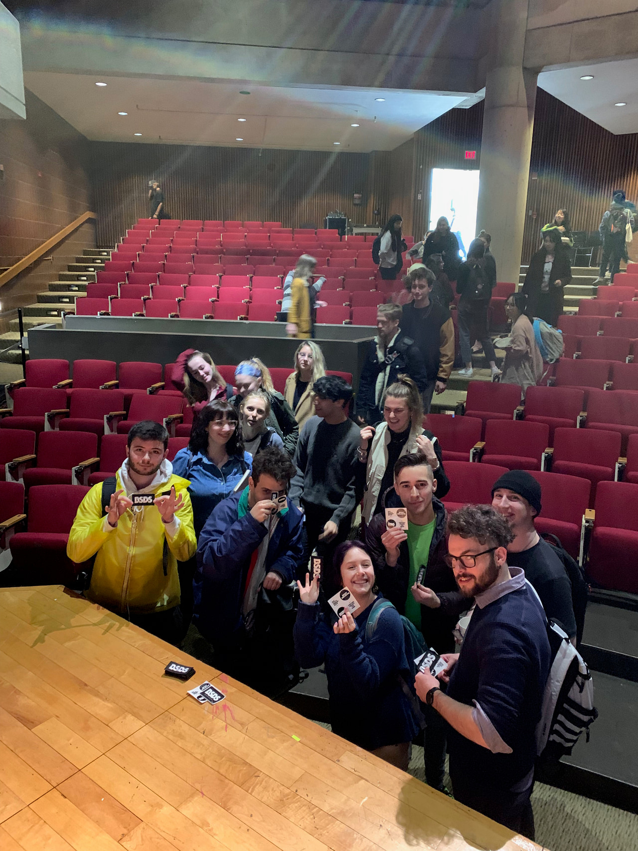 A group poses among rows of red auditorium seats.