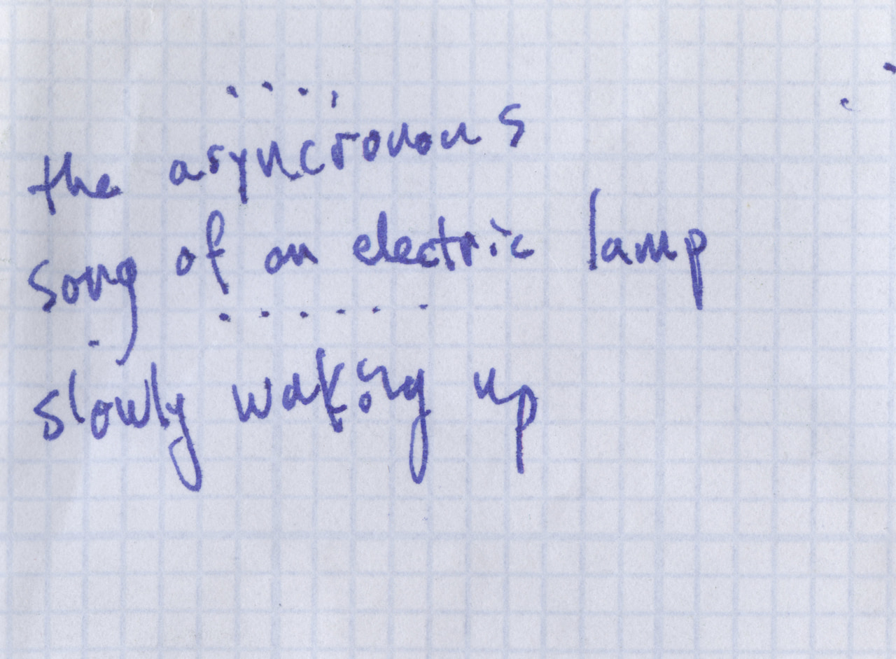 Blue handwritten poem on graph paper: The asynchronous song of an electric lamp slowly waking up.