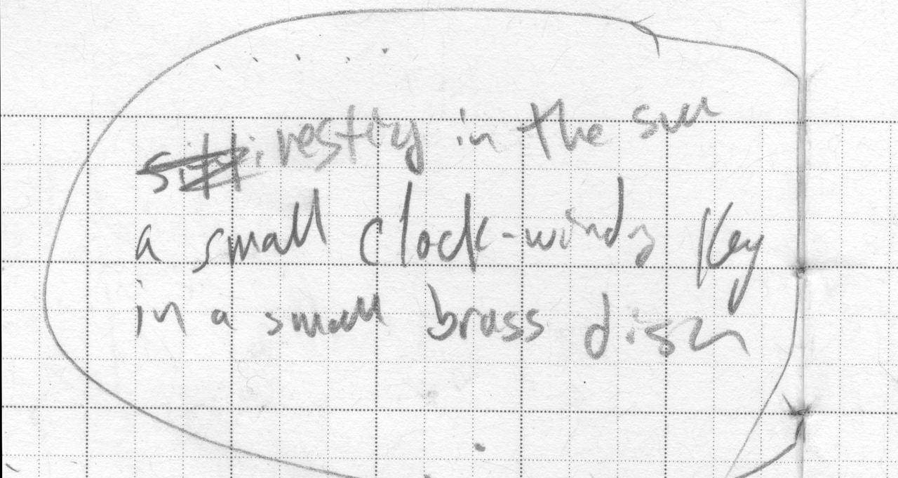 Circled handwritten poem draft with a crossed-out revision: A small clock-wound key in a small brass dish.