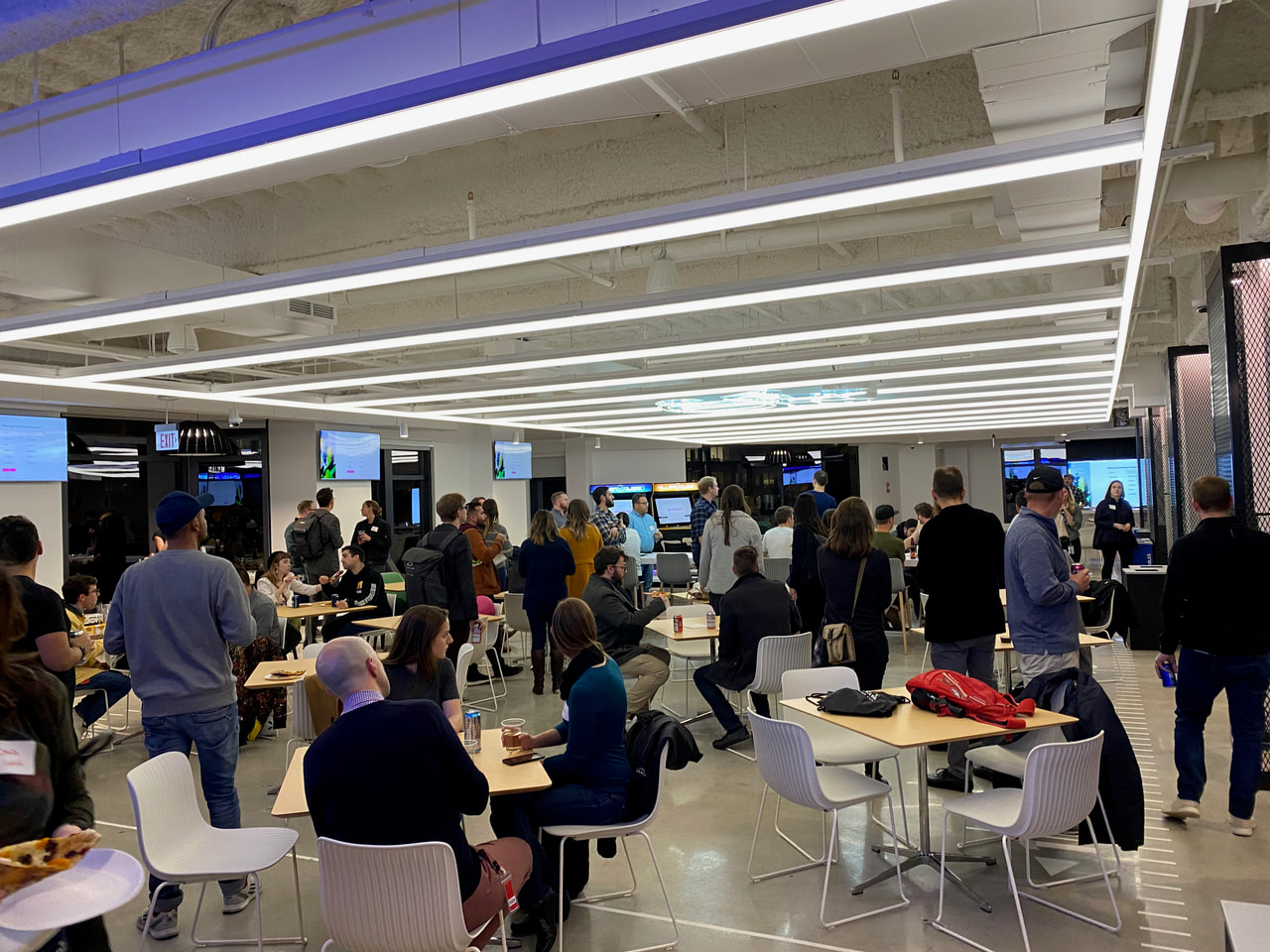 People gather around white tables in a brightly lit room.